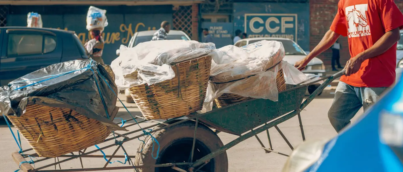 Baskets of goods on a wheelbarrow on a busy Lusaka street
